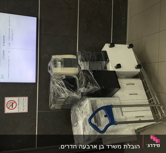 עגלת מתכת עם ארגזים וציוד עטופים בניילון
